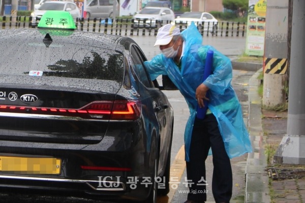 바르게살기운동 광주광역시 광산구협의회 홍연기 부홰장이 택시가 정차하자 태극기를 전하고 있다.