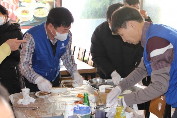 어르신들이 떡국 점심을 마치자 운남동 바르게살기위원회 윤용조 위원장과 최준홍 위원이 상을 치우고 있다.