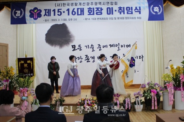 (사)한국생활개선 광주광역시연합회 제15대 변옥례 회장이 제16대 정미자 회장에게 연합회기를 인계하자 정미자 회장이 회기를 힘차게 흔들고 있다.