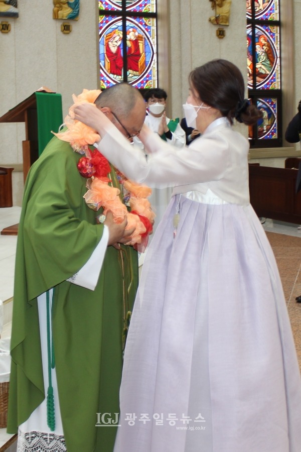 사제서품 25주년 은경축을 맞이한 천주교 광주대교구 운남동성당 조정훈 안토니오 주임신부에게 신자들을 대표해서 김란희 마리아막달레나 자매가 축하 화환을 걸어주고 있다.