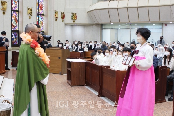 사제서품 25주년 은경축을 맞이한 조정훈 안토니오 신부에게 신자들의 영적 예물을 김명란 데레사 자매가 전달하고 있다.