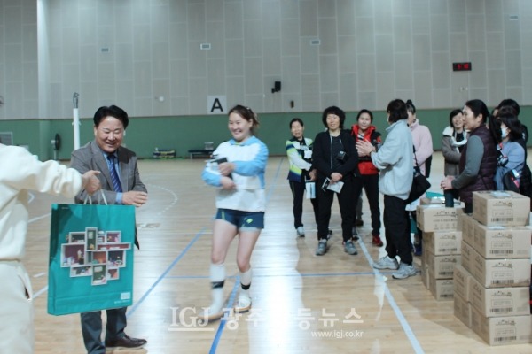 ‘2023년 광산구 자모배구 한마당’ 경품에 당첨된 어룡초 OB 허정임 선수가 추첨한 김성진 이사장에게 뛰어오는 동안 김성진 이사장에게 선물이 건네지고 있다.