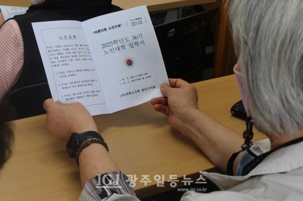 광산구 노인대학 제36기 입학식 노인강령 낭독 순서에서 노인강령을 살피는 신입생 모습.