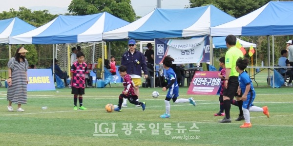 ‘2023 광산구 I – LEAGUE’ U-10  경기에서 단독드리블을 하는 선수와 이를 제지하기 위해 머리를 휘날리며 달여오는 선수들 모습.