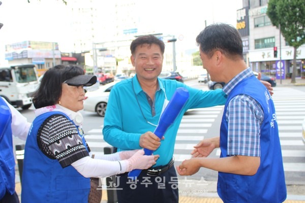 바르게살기운동 광산구협의회 김열화 부회장과 월곡1동 위원인 박균택 변호사가 박 변호사를 보고 차를 세운 개인택시 기사에게 태극기를 전하고 환하게 웃고 있다.