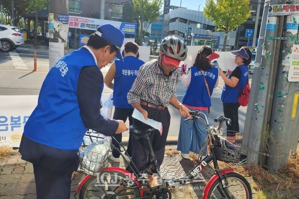 바르게살기운동 광주 광산구협의회 김병우 회장이 자전거를 타고 지나가는 어르신에게 기념품을 전달하며 캠페인을 벌이고 있다. (사진 제공 : 바르게살기운동 광산구협의회 정안숙 사무국장)